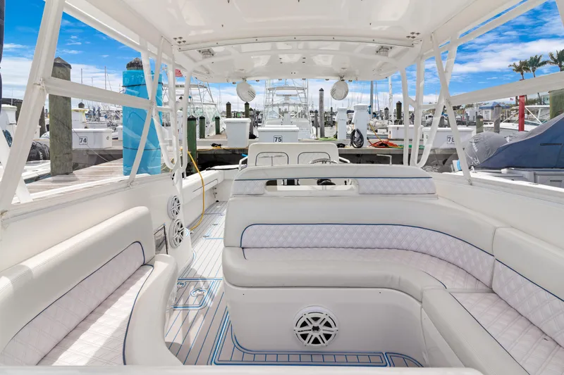 Slide: The Image of 2004 Intrepid 377 Walkaround boat interior with white seating and marina view. - 19