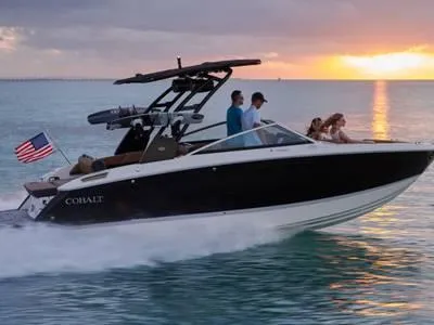 Slide: The Image of 2021 Cobalt R6 boat cruising at sunset with passengers, American flag waving. - 1