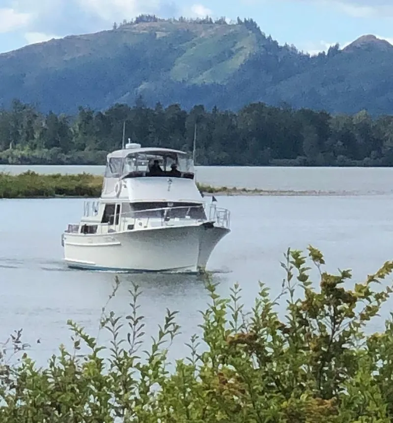 Slide: The Image of 1981 Tollycraft 43 Motoryacht cruising on a scenic lake with mountainous backdrop. - 1