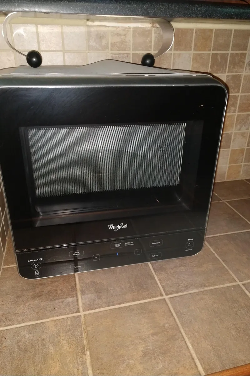 Slide: The Image of Compact black microwave on tiled kitchen counter, featuring Whirlpool branding. - 22