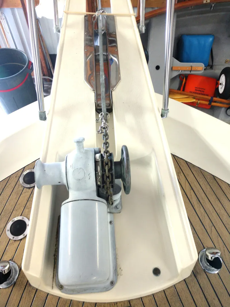 Slide: The Image of 1981 Tollycraft 43 Motoryacht anchor windlass on teak deck, with visible chain and railing. - 47