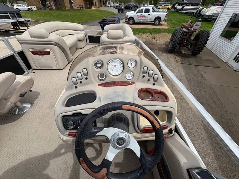 Slide: The Image of 2011 Sun Tracker PARTY BARGE 25 dashboard with steering wheel and gauges, parked outdoors. - 21