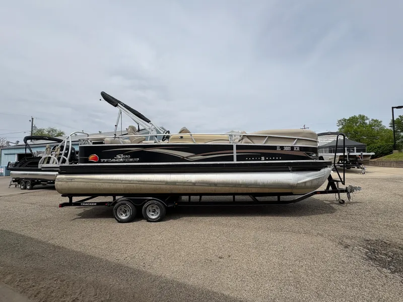 Slide: The Image of 2011 Sun Tracker PARTY BARGE 25 pontoon boat on a trailer, parked outdoors. - 4