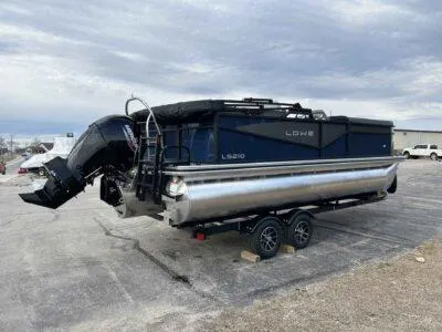 Slide: The Image of 2025 Lowe LS 210 WT pontoon boat on trailer, parked outdoors under cloudy sky. - 2