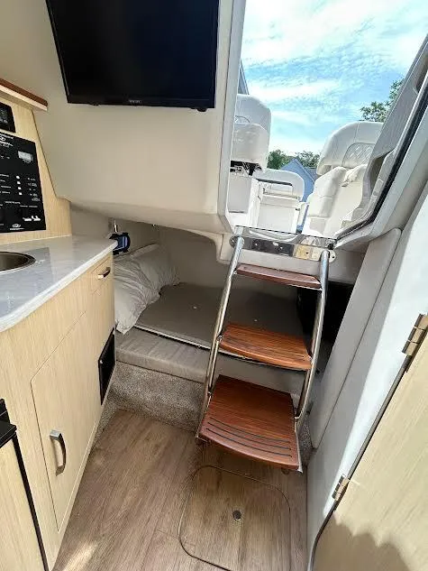 Slide: The Image of 2024 Regal 26 XO cabin interior with wooden steps, kitchenette, and cozy sleeping area. - 5