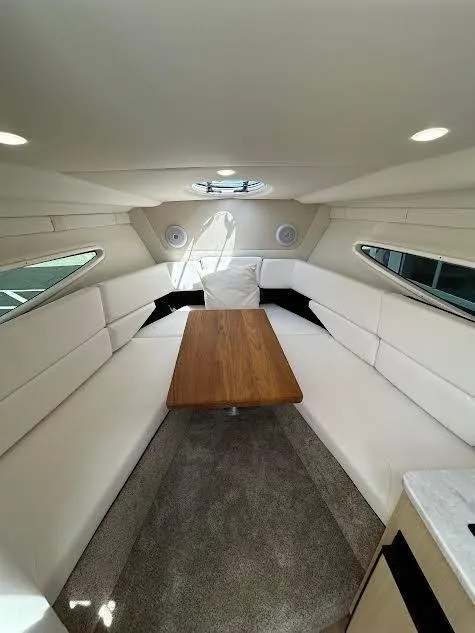 Slide: The Image of 2024 Regal 26 XO cabin interior with white seating and wooden table. - 6