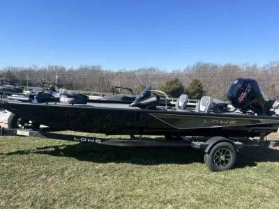 Slide: The Image of 2025 Lowe Stinger 195 Bass boat on trailer, parked on grass under clear blue sky. - 3