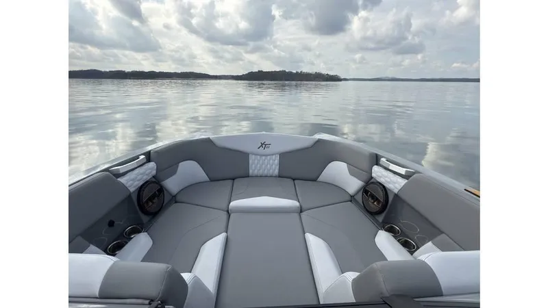 Slide: The Image of 2023 MasterCraft XT22 boat interior with gray seating on a calm lake. - 12
