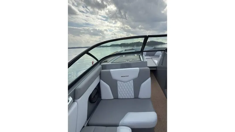 Slide: The Image of 2023 MasterCraft XT22 boat interior with gray seating, lake view, and cloudy sky. - 13