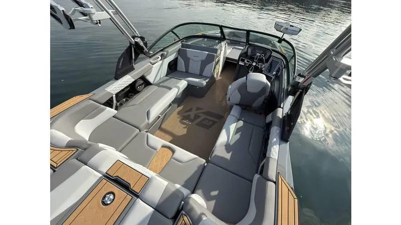 Slide: The Image of 2023 MasterCraft XT22 boat interior with spacious seating and modern dashboard on calm water. - 15