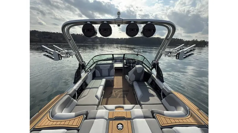 Slide: The Image of 2023 MasterCraft XT22 boat interior with sleek seating and advanced sound system on a calm lake. - 16