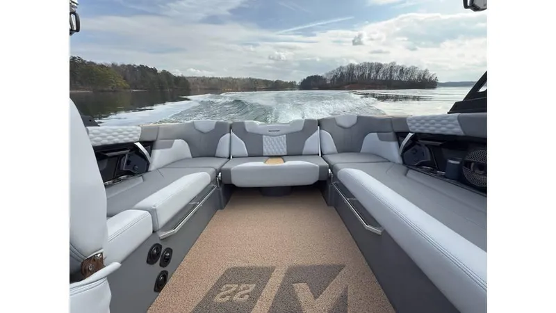 Slide: The Image of 2023 MasterCraft XT22 boat interior with gray seating, cruising on a lake. - 7