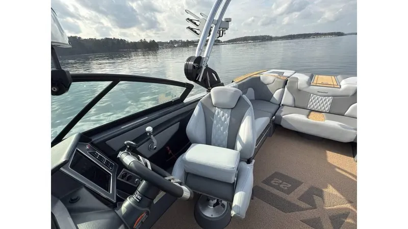 Slide: The Image of 2023 MasterCraft XT22 boat interior with sleek seating and modern dashboard on a calm lake. - 8