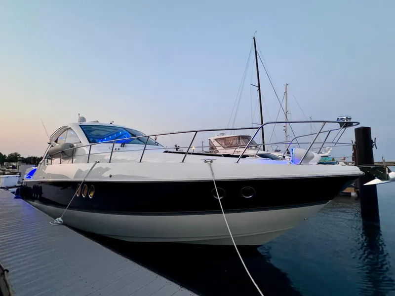 Slide: The Image of 2014 Cruisers Yachts 54 Sport Coupe docked at sunset, featuring sleek design and modern amenities. - 2