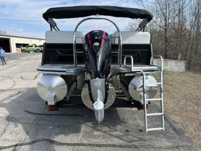 Slide: The Image of 2025 Lowe SS 230 WT pontoon boat with outboard motor and ladder, parked outdoors. - 2