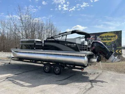 Slide: The Image of 2025 Lowe SS 230 WT pontoon boat on trailer, parked outdoors near BlackBeard Marine sign. - 7