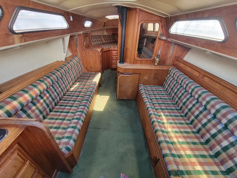 Slide: The Image of 1977 Islander 27 sailboat interior with plaid seating, wood paneling, and green carpet. - 11