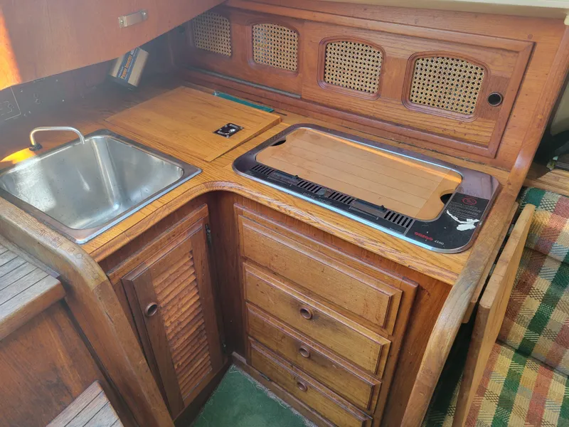 Slide: The Image of 1977 Islander 27 yacht interior with wooden cabinetry, sink, and stove. - 12