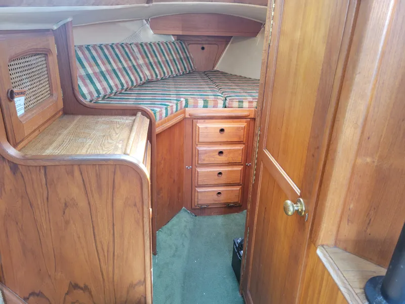 Slide: The Image of 1977 Islander 27 sailboat interior with wood paneling and striped cushions. - 16