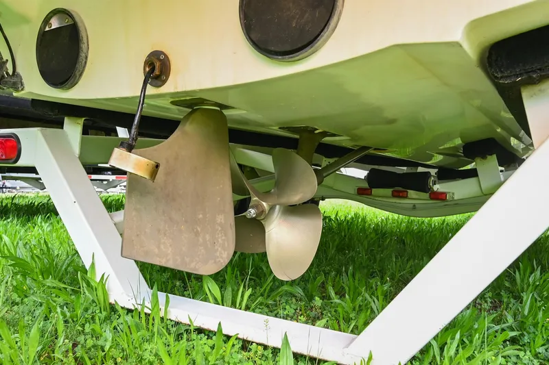 Slide: The Image of 2001 MasterCraft MariStar 230 boat propeller and rudder on trailer, resting on grass. - 26