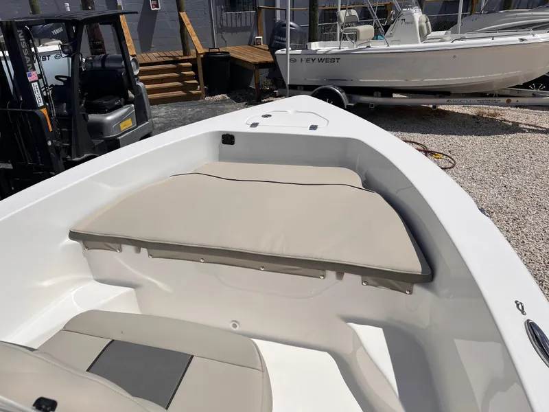 Slide: The Image of 2025 Key West 179 FS boat interior with beige seating, parked outdoors. - 13