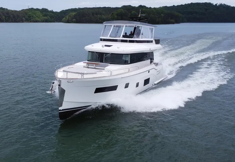 Slide: The Image of 2021 Sirena 58 yacht cruising on a serene lake with lush green surroundings. - 2