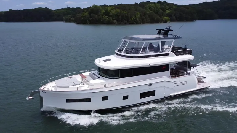 Slide: The Image of 2021 Sirena 58 yacht cruising on a serene lake with lush green surroundings. - 6