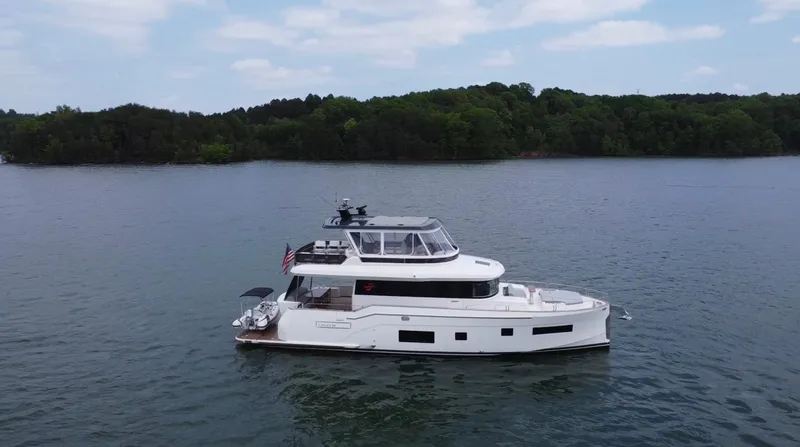Slide: The Image of 2021 Sirena 58 yacht cruising on a serene lake with lush green shoreline. - 8