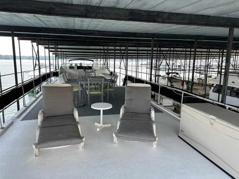 Slide: The Image of Rooftop deck of 1992 Sumerset 14x70 houseboat with lounge chairs and table under covered dock. - 15