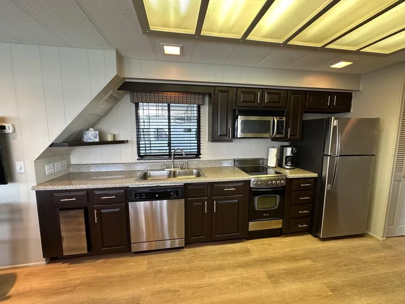 Slide: The Image of Modern kitchen in a 1992 Sumerset 14x70 houseboat with stainless steel appliances and dark wood cabinets. - 4