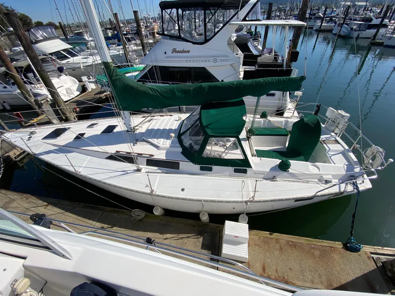 Slide: The Image of 1989 Hunter Legend 40 sailboat docked in marina, featuring green sail covers. - 0