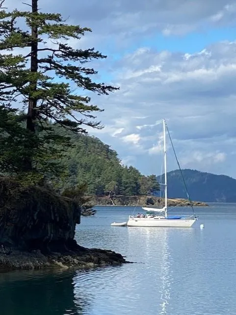 Slide: The Image of Sailboat Hunter Legend 40 (1989) anchored near forested coastline under cloudy sky. - 1