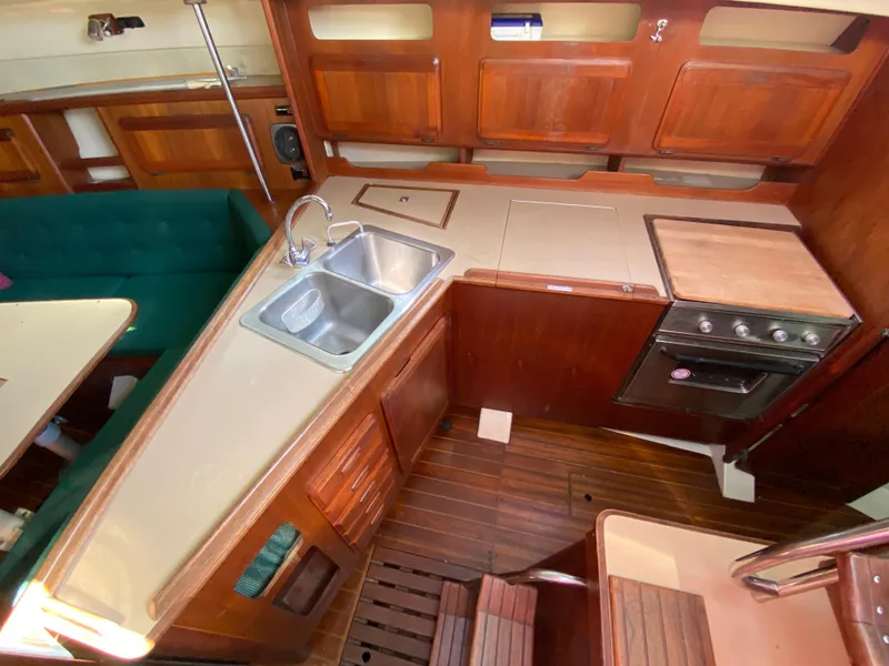 Slide: The Image of 1989 Hunter Legend 40 yacht interior with wooden cabinetry, sink, stove, and green seating. - 11