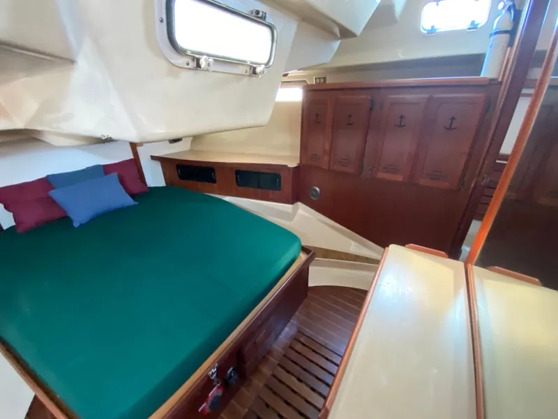 Slide: The Image of 1989 Hunter Legend 40 yacht cabin with green bed, wooden cabinets, and porthole window. - 17