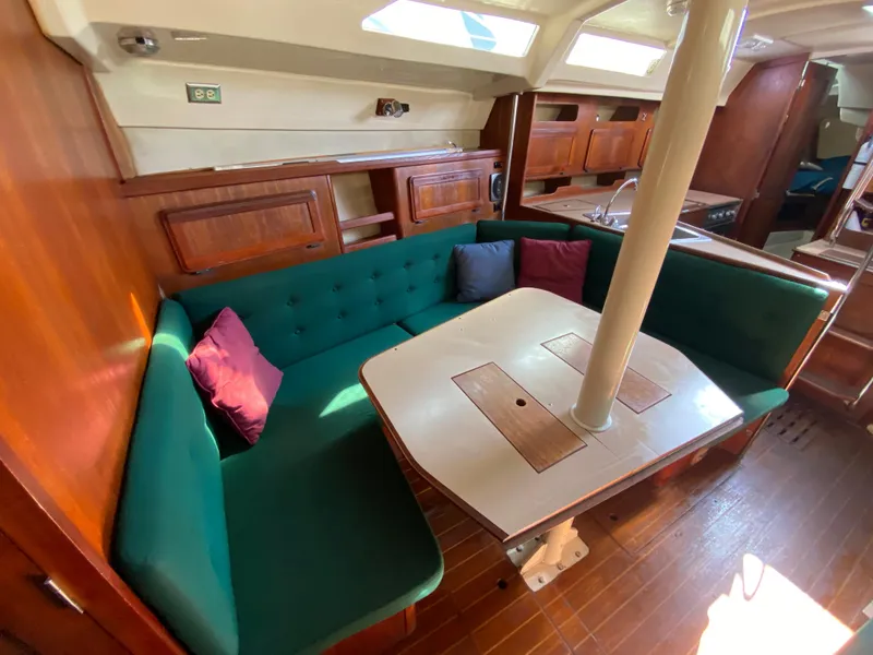 Slide: The Image of 1989 Hunter Legend 40 yacht interior with green cushioned seating and wooden table. - 6
