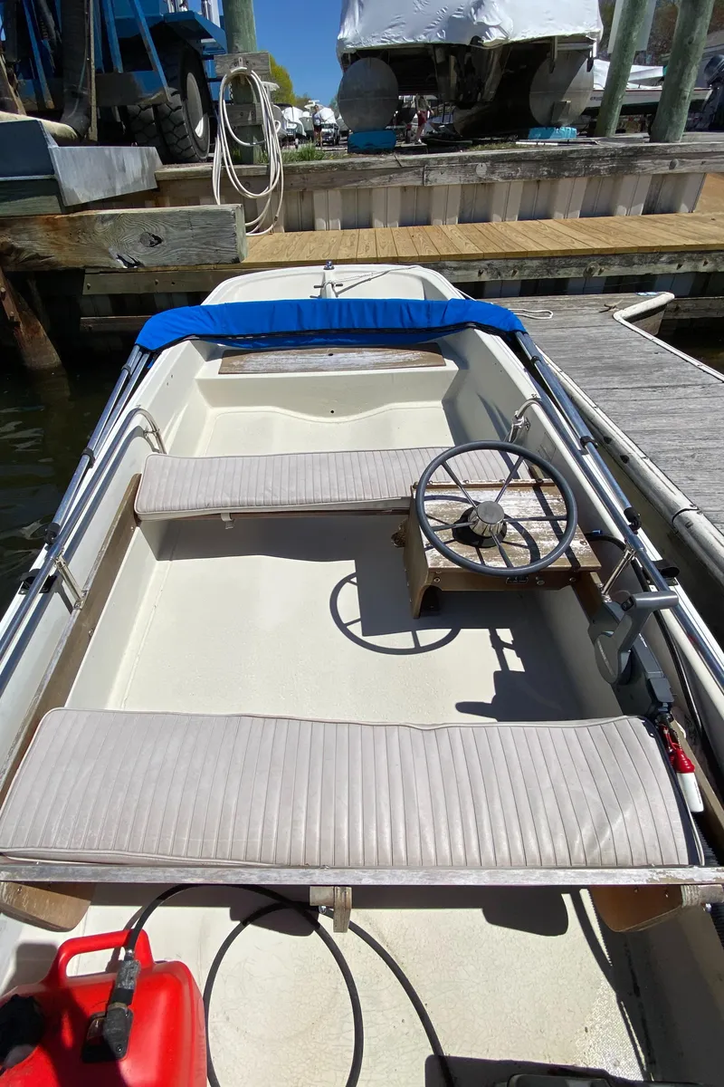 Slide: The Image of 1974 Boston Whaler 13 boat interior with steering wheel and seating, docked at marina. - 2