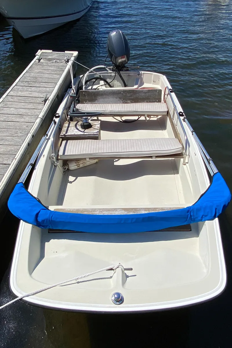 Slide: The Image of 1974 Boston Whaler 13 boat docked, featuring classic design and blue bumper. - 4