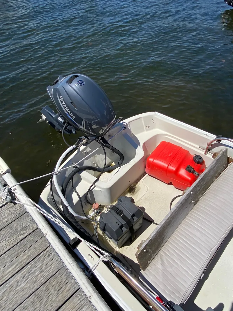 Slide: The Image of 1974 Boston Whaler 13 boat with outboard motor and red fuel tank, docked on water. - 7