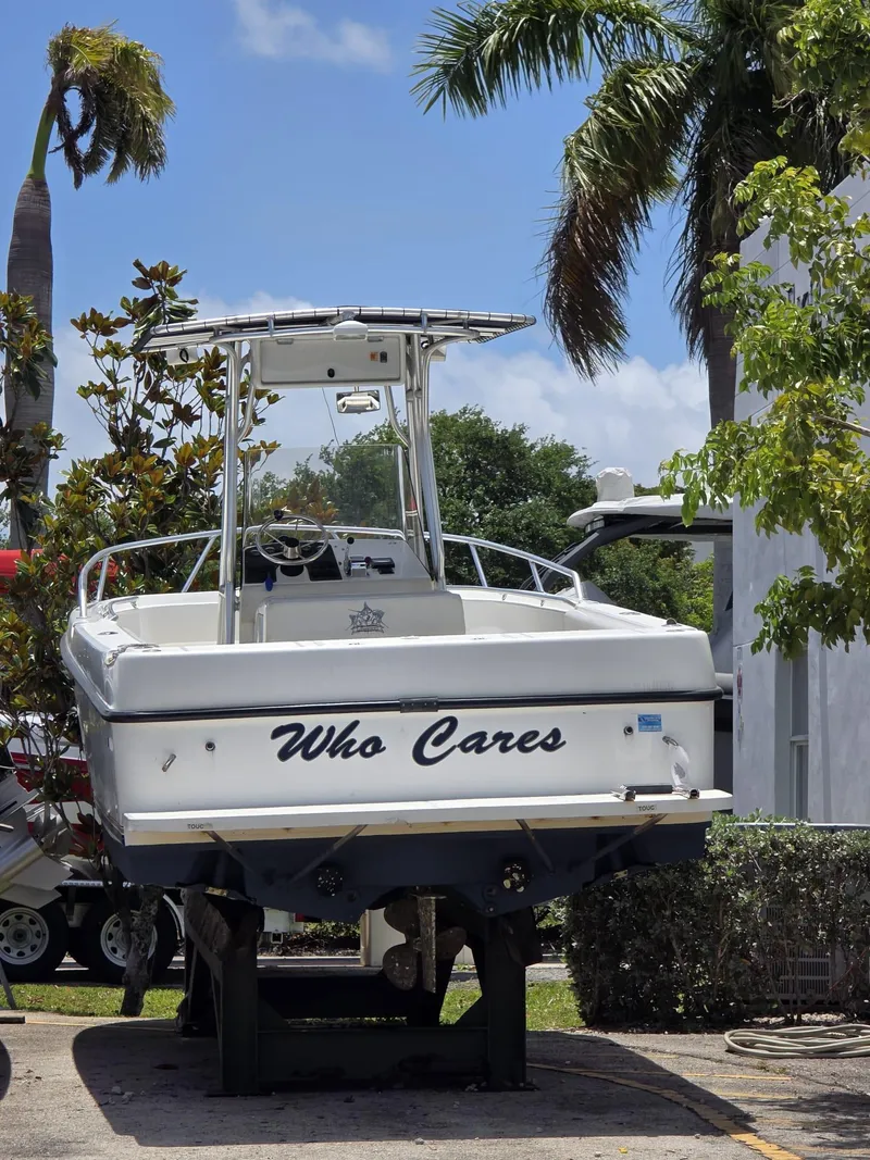 Slide: The Image of 1999 Shamrock 246 Open boat named "Who Cares" on display, surrounded by tropical trees. - 3