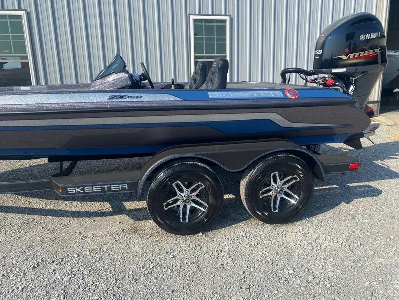 Slide: The Image of 2025 Skeeter ZX150 boat with Yamaha engine, parked on gravel near a metal building. - 5
