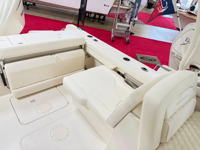 Slide: The Image of 2025 Grady-White Freedom 235 boat interior with white seating and red carpet backdrop. - 8