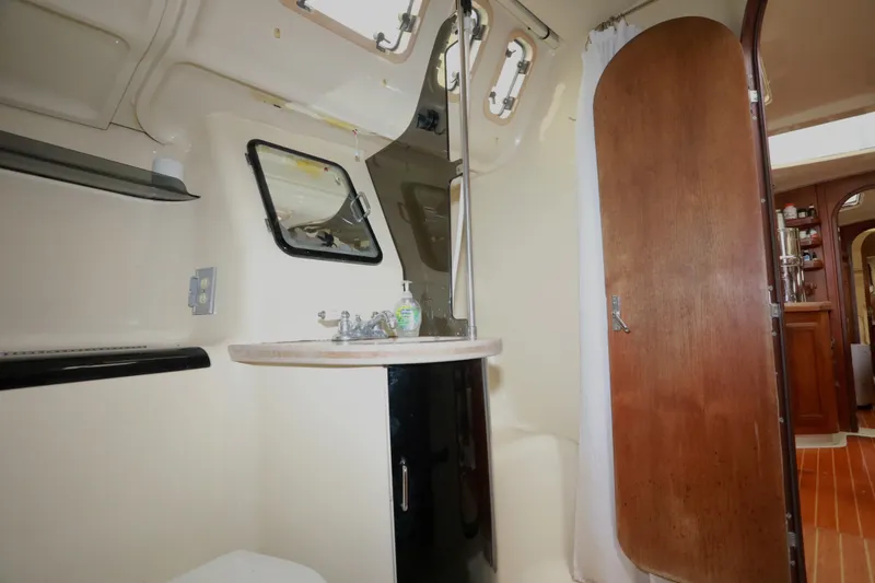 Slide: The Image of Interior of 1995 Hunter 430 sailboat bathroom with sink, mirror, and wooden door. - 32