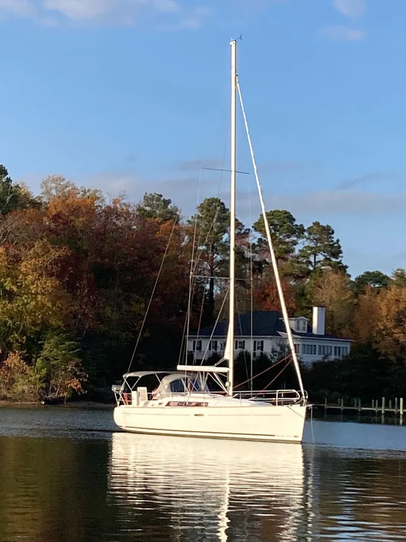 The Image of 2015 Beneteau Oceanis 37 Platinum sailboat on calm water, surrounded by autumn trees. - 0