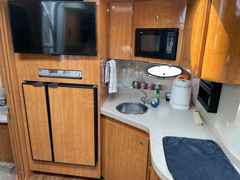 Slide: The Image of 2003 Regal 3860 Commodore yacht kitchen with wood cabinets, sink, microwave, and refrigerator. - 10
