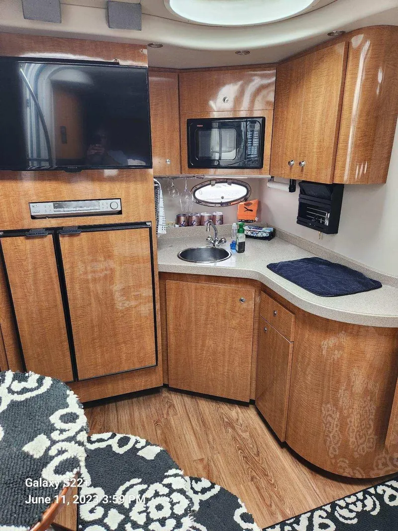 Slide: The Image of 2003 Regal 3860 Commodore yacht kitchen with wood cabinets, TV, and appliances. - 2