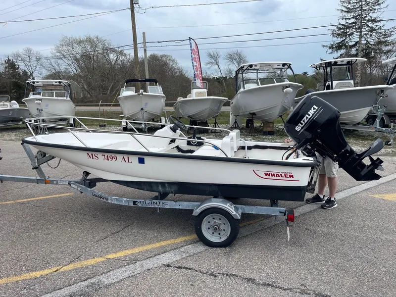 Slide: The Image of 2005 Boston Whaler 150 Sport boat on trailer, parked with other boats in background. - 2