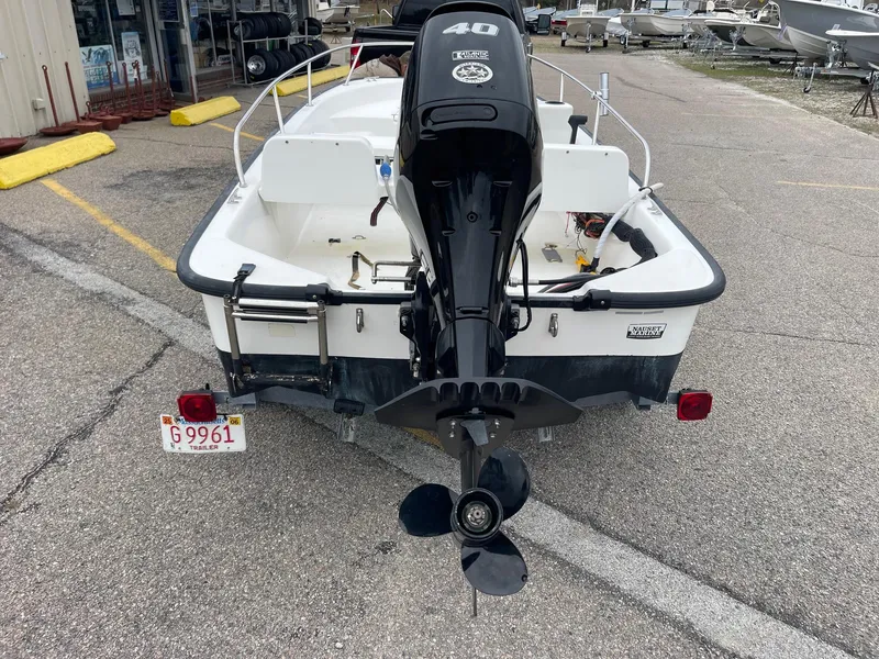 Slide: The Image of 2005 Boston Whaler 150 Sport boat, rear view with outboard motor, parked on pavement. - 5