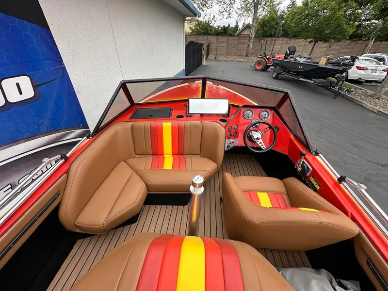 Slide: The Image of 1988 Malibu Skier boat interior with red, yellow, and brown seating, parked outdoors. - 11
