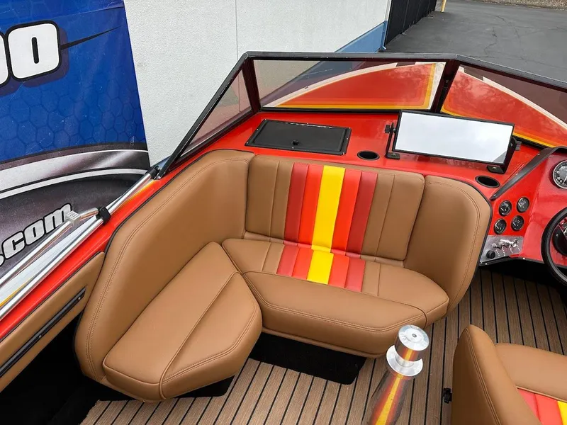 Slide: The Image of 1988 Malibu Skier boat interior with tan and striped seating, red dashboard, and modern controls. - 12
