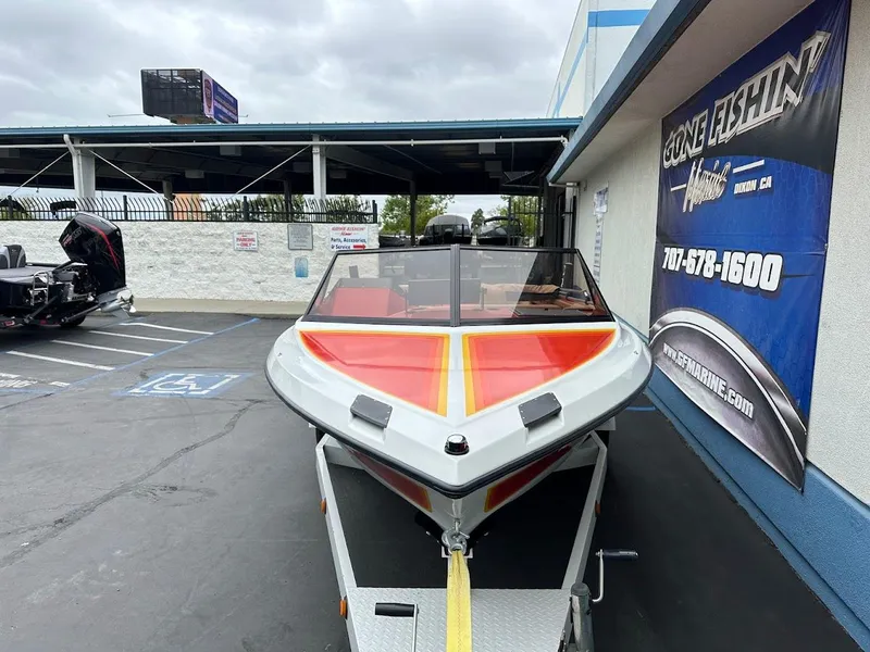 Slide: The Image of 1988 Malibu Skier boat with vibrant red and yellow design, parked outside a dealership. - 2